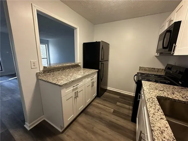 a kitchen with granite countertop a sink stove and refrigerator