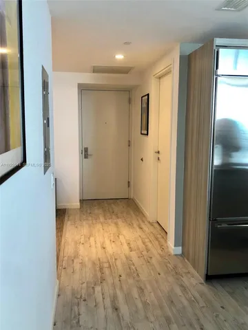 a view of a livingroom with wooden floor and a kitchen