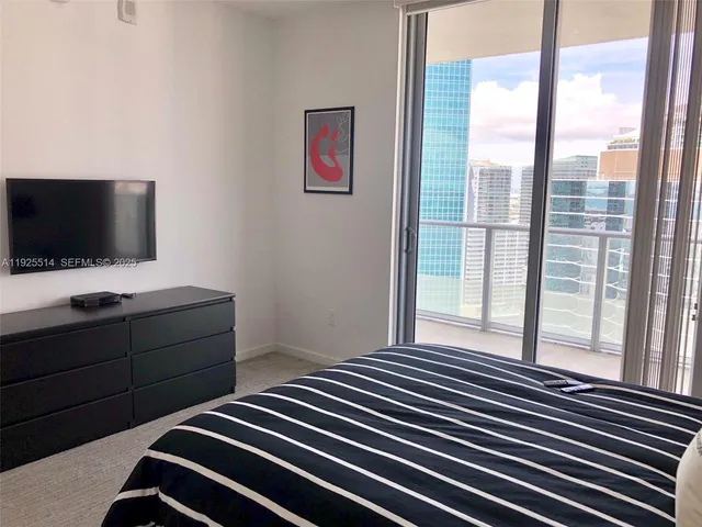 a bedroom with a bed and a flat tv screen next to a window