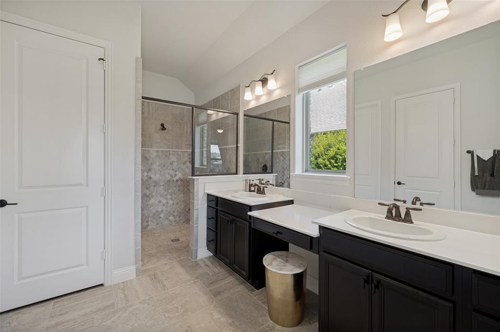 7821 Kentmere The Colony, TX 75056 - Photo 18 of 40 The luxurious primary ensuite offers a spa-inspired retreat with dual vanities, expansive quartz countertops, and abundant storage. A spacious walk-in shower with designer tile, frameless glass enclosure, and elegant finishes is complemented by soaring ceilings and natural light, creating a bright and sophisticated space for everyday relaxation.