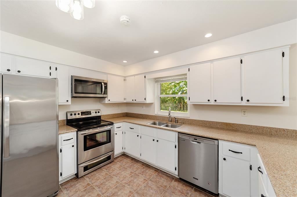 4805 Southwest 19th Street Gainesville, FL 32608 - Photo 20 of 43 a kitchen with stainless steel appliances granite countertop a sink a stove a refrigerator a window and white cabinets