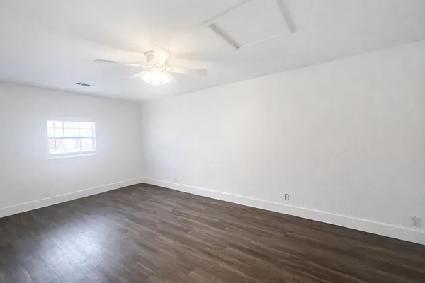 an empty room with wooden floor and fan
