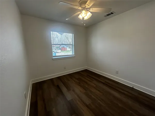 en empty room with wooden floor and windows