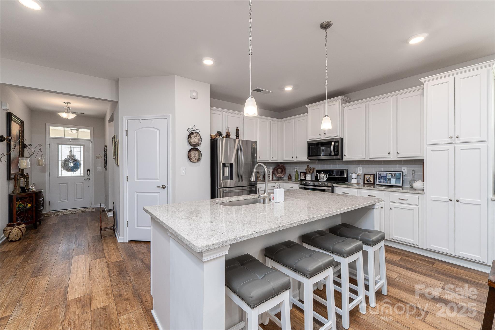 550 Rustlewood Way Rock Hill, SC 29732 - Photo 21 of 33 a kitchen with stainless steel appliances kitchen island granite countertop a stove a refrigerator a sink a dining table and chairs with wooden floor