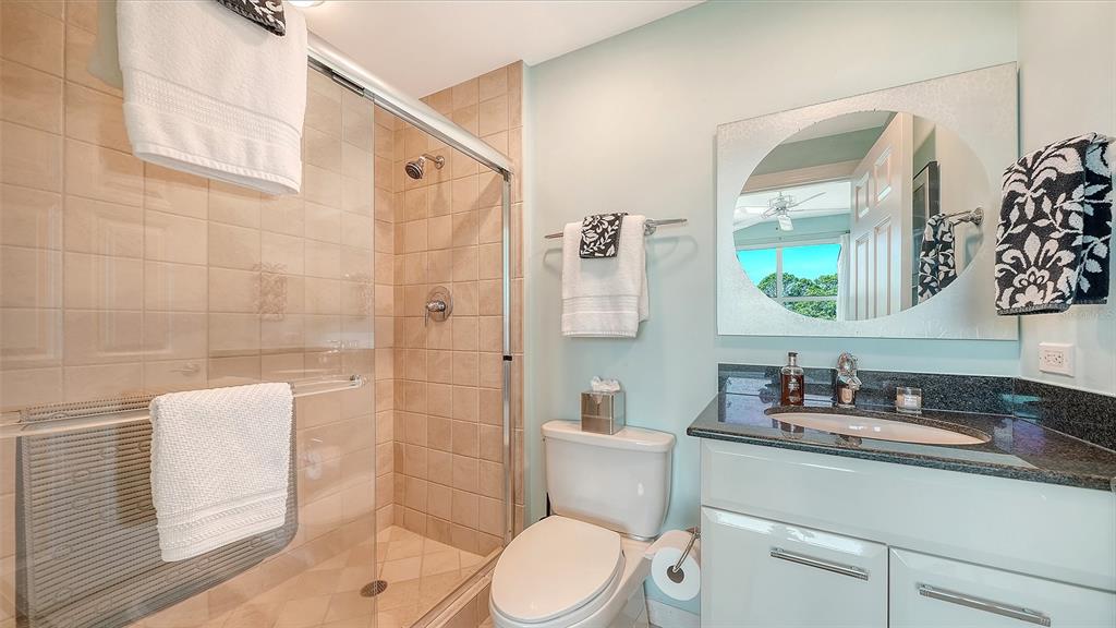 409 North Point Road, Unit 401 Osprey, FL 34229 - Photo 42 of 90 a bathroom with a granite countertop sink toilet a mirror and shower