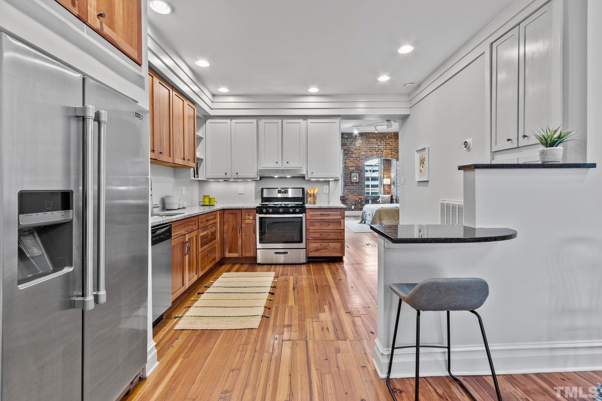 323 West Main Street, Unit J Durham, NC 27701 - Photo 11 of 36 a kitchen with stainless steel appliances a sink a stove a refrigerator cabinets and a dining table