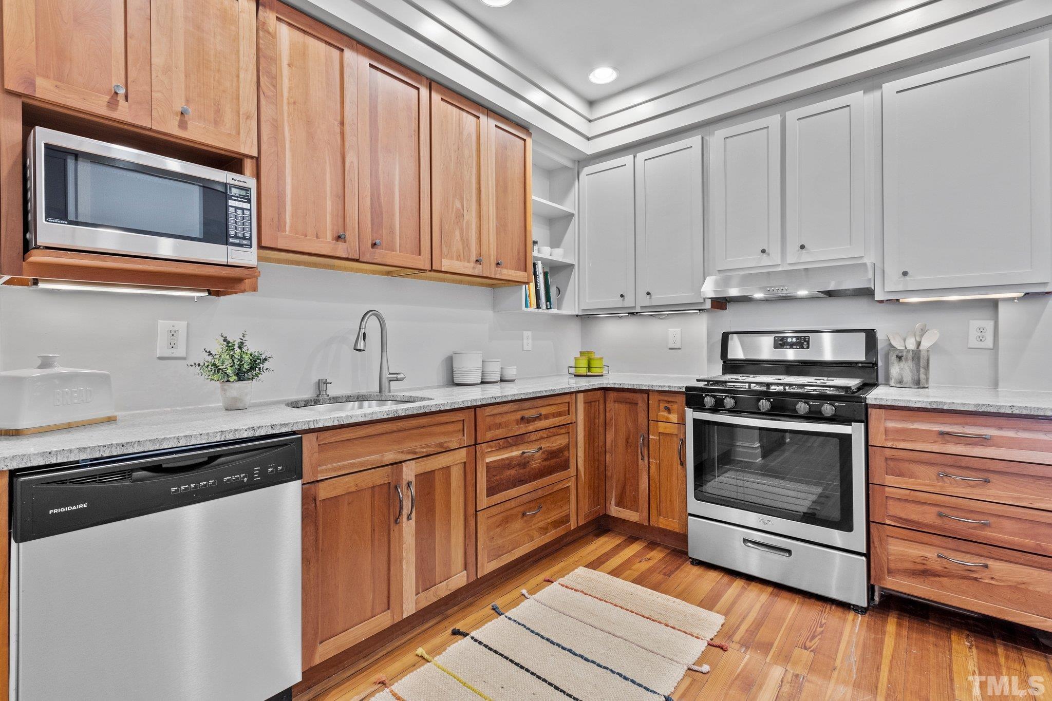 323 West Main Street, Unit J Durham, NC 27701 - Photo 12 of 36 a kitchen with granite countertop wooden cabinets and stainless steel appliances