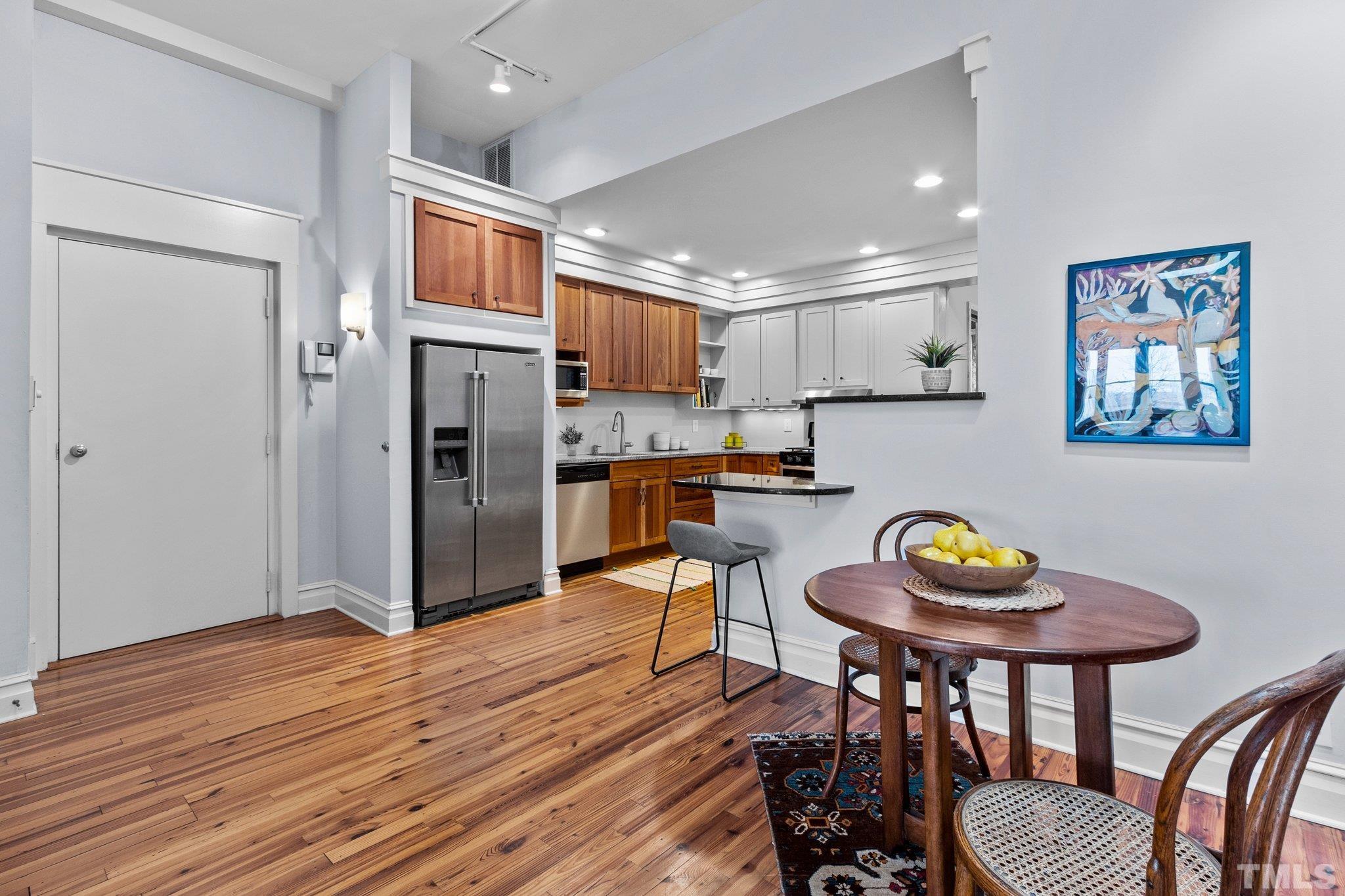 323 West Main Street, Unit J Durham, NC 27701 - Photo 10 of 36 a kitchen with stainless steel appliances wooden floors and a refrigerator
