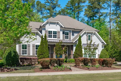 a front view of a house with a yard and potted plants