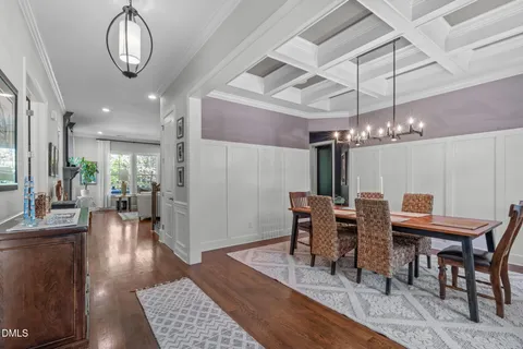 a kitchen with stainless steel appliances kitchen island granite countertop a table chairs and a wooden floor