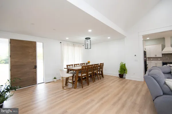 a living room with couches and kitchen view with wooden floor