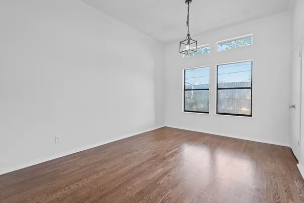 a view of a room with wooden floor chandelier and windows