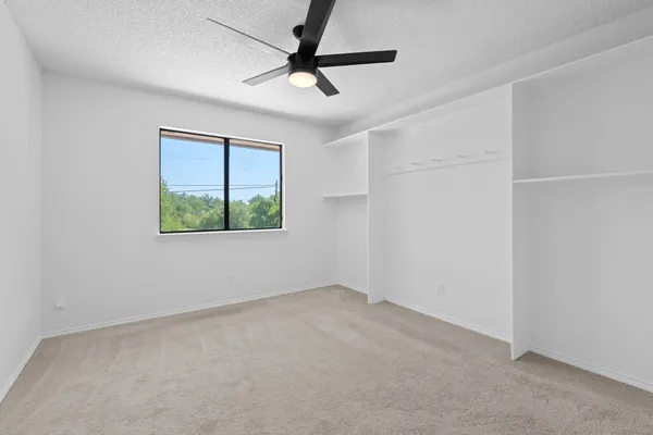 an empty room with a window and a fan