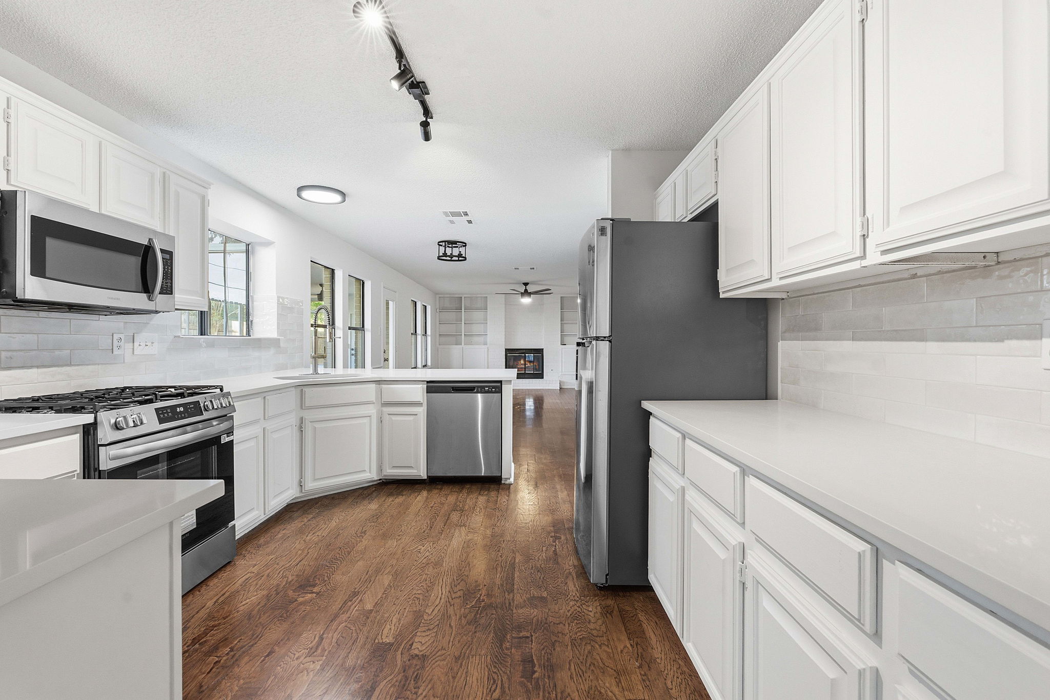 1106 Split Oak Cove Pflugerville, TX 78660 - Photo 5 of 27 a kitchen with stainless steel appliances granite countertop a refrigerator a stove top oven a sink dishwasher and white cabinets with wooden floor