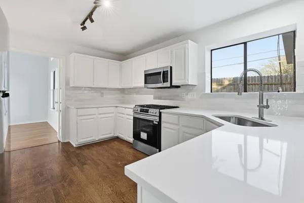 a kitchen with granite countertop a stove top oven sink and cabinets