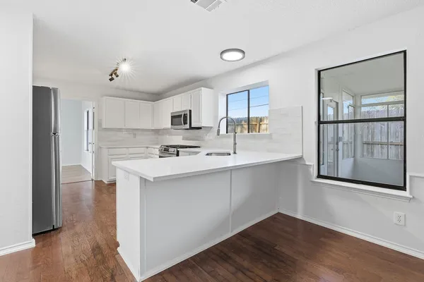 a kitchen with stainless steel appliances a sink a stove a refrigerator and cabinets