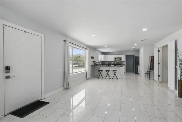 a view of a livingroom with table & chairs a ceiling fan and entryway
