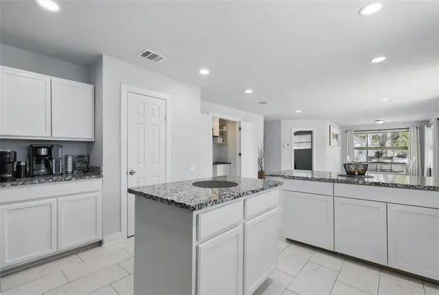 a kitchen with granite countertop a sink and white cabinets