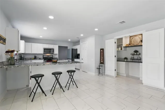 a kitchen with stainless steel appliances kitchen island granite countertop a refrigerator and cabinets