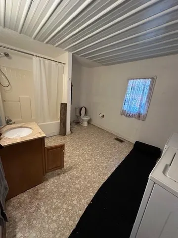 a bed sitting in a bedroom next to a window and a chandelier