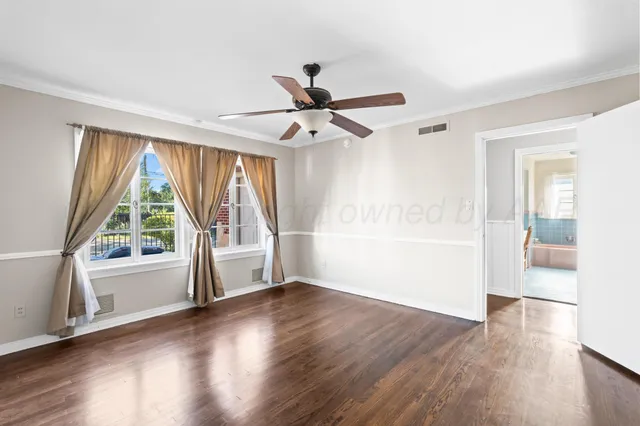a view of an empty room with a window and wooden floor