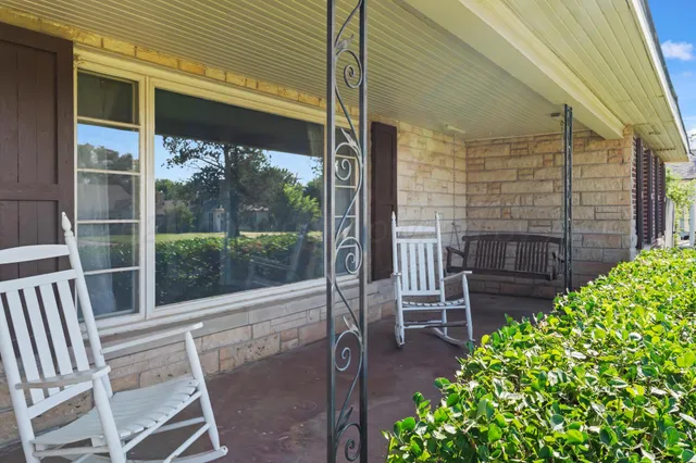 a balcony with table and chairs and potted plants