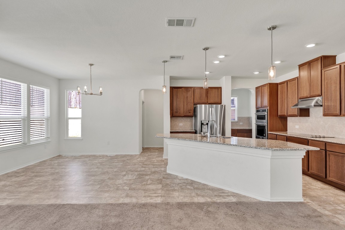 195 Azure Cove Kyle, TX 78640 - Photo 15 of 32 Kitchen featuring arched walkways, hanging light fixtures, brown cabinets, and recessed lighting