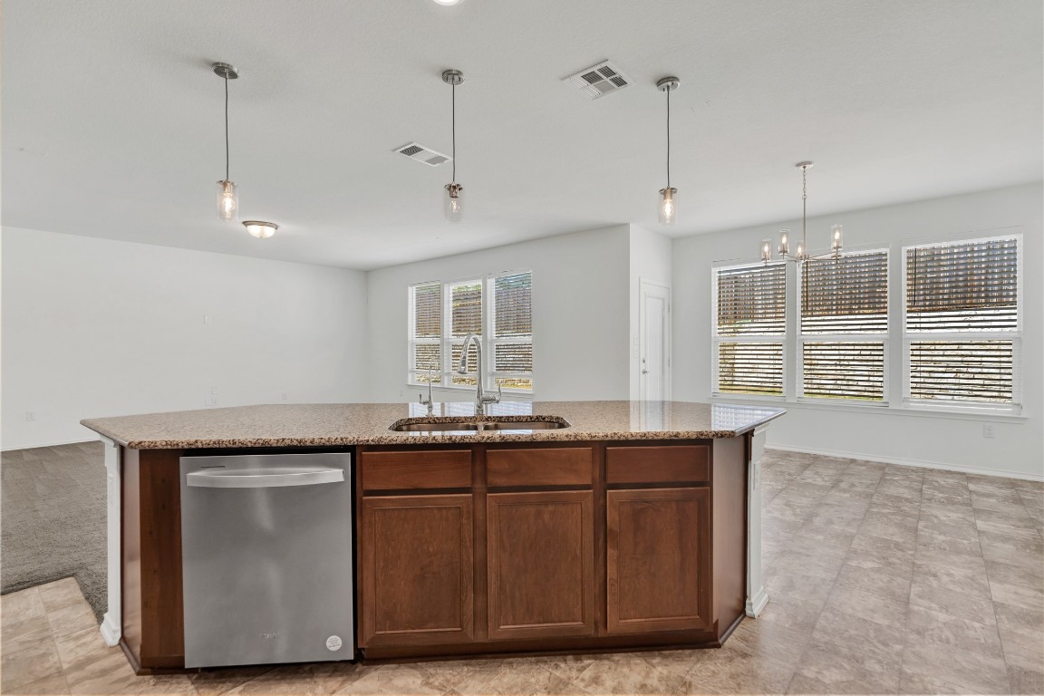 195 Azure Cove Kyle, TX 78640 - Photo 16 of 32 Kitchen featuring pendant lighting, dishwasher, an island with sink, a chandelier, and light stone countertops