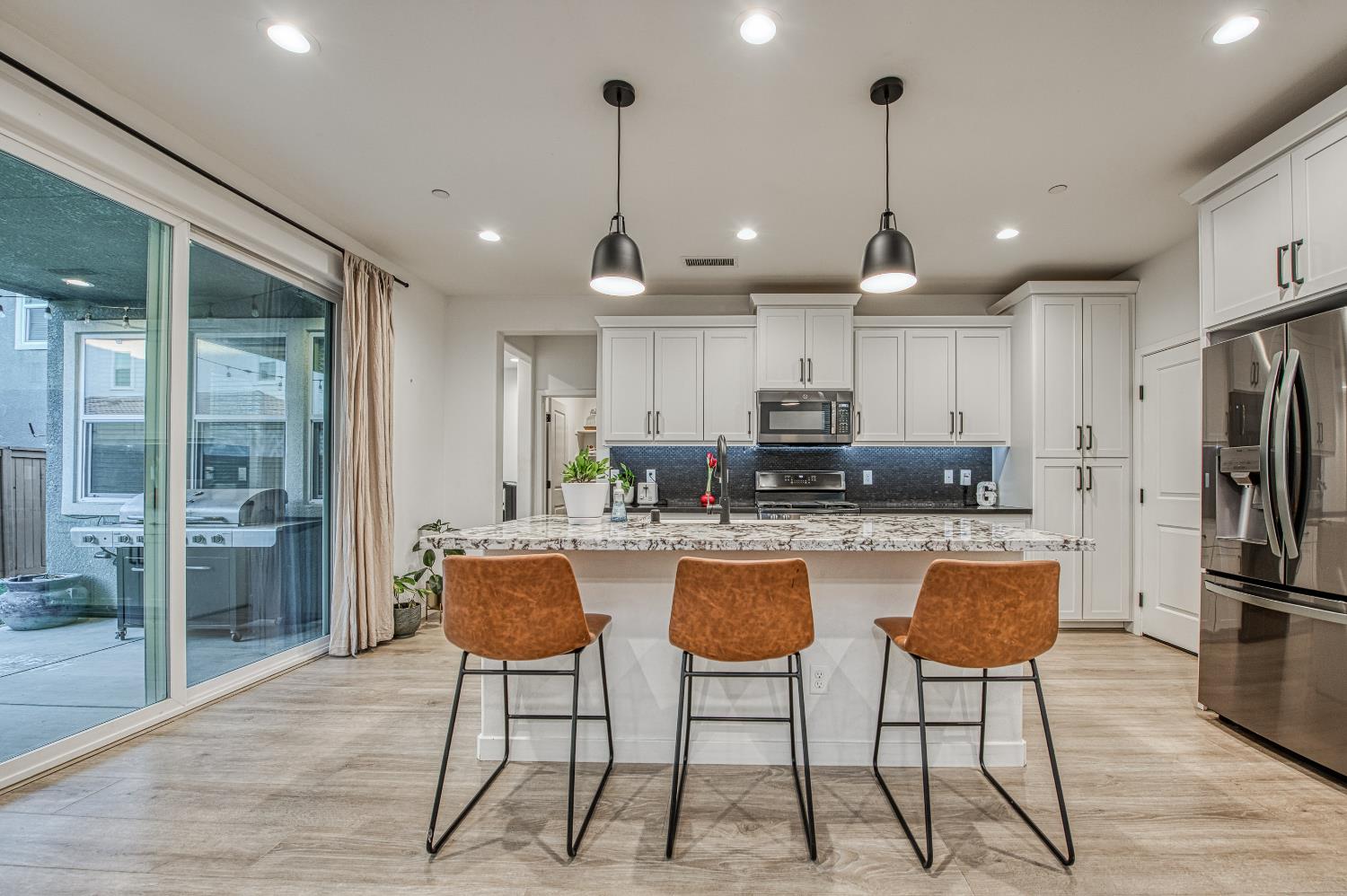 4311 San Miguel Road Madera, CA 93636 - Photo 11 of 79 a kitchen with stainless steel appliances granite countertop a stove a refrigerator a oven a sink a island with a dining table and chairs