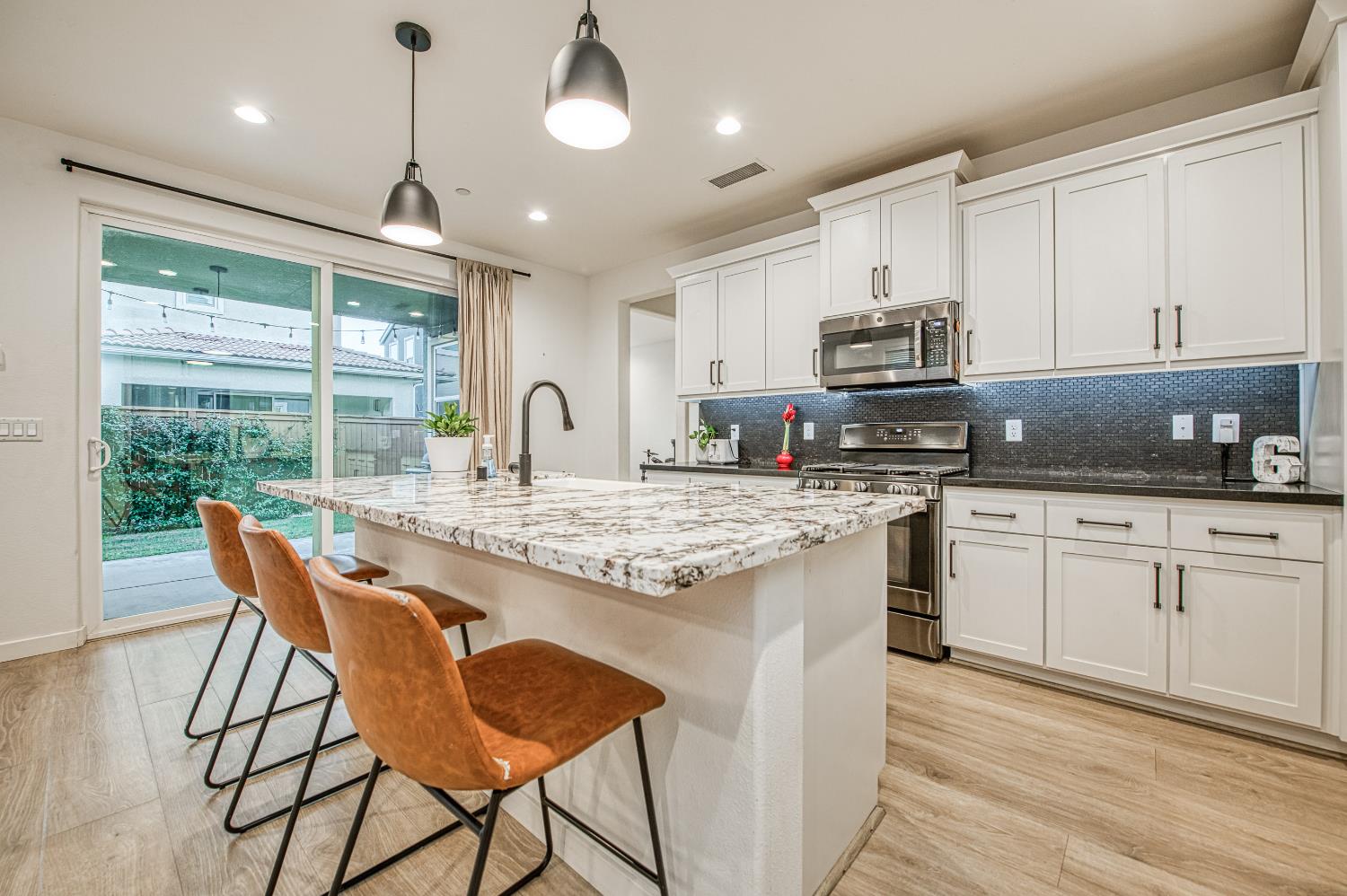 4311 San Miguel Road Madera, CA 93636 - Photo 13 of 79 a kitchen with stainless steel appliances granite countertop a stove a sink a microwave a island with a dining table and chairs