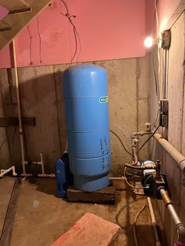 a room with water heater and wooden cabinets