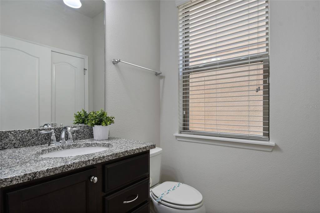 8869 Rhodes Street Kissimmee, FL 34747 - Photo 18 of 66 a bathroom with a granite countertop sink and a toilet