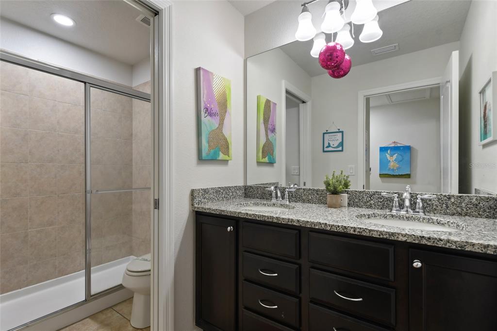 8869 Rhodes Street Kissimmee, FL 34747 - Photo 33 of 66 a bathroom with a granite countertop sink toilet a large mirror a vanity and shower