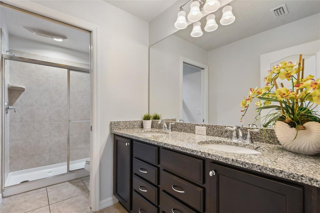 8869 Rhodes Street Kissimmee, FL 34747 - Photo 36 of 66 a bathroom with a granite countertop sink a mirror and a shower