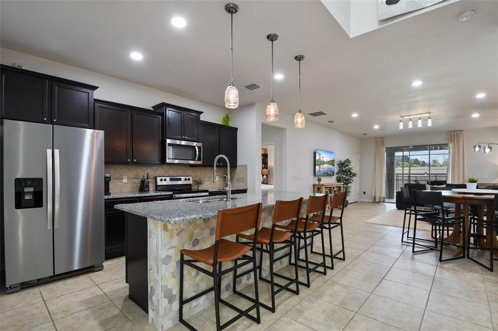 8869 Rhodes Street Kissimmee, FL 34747 - Photo 6 of 66 a kitchen with stainless steel appliances a table chairs refrigerator and microwave