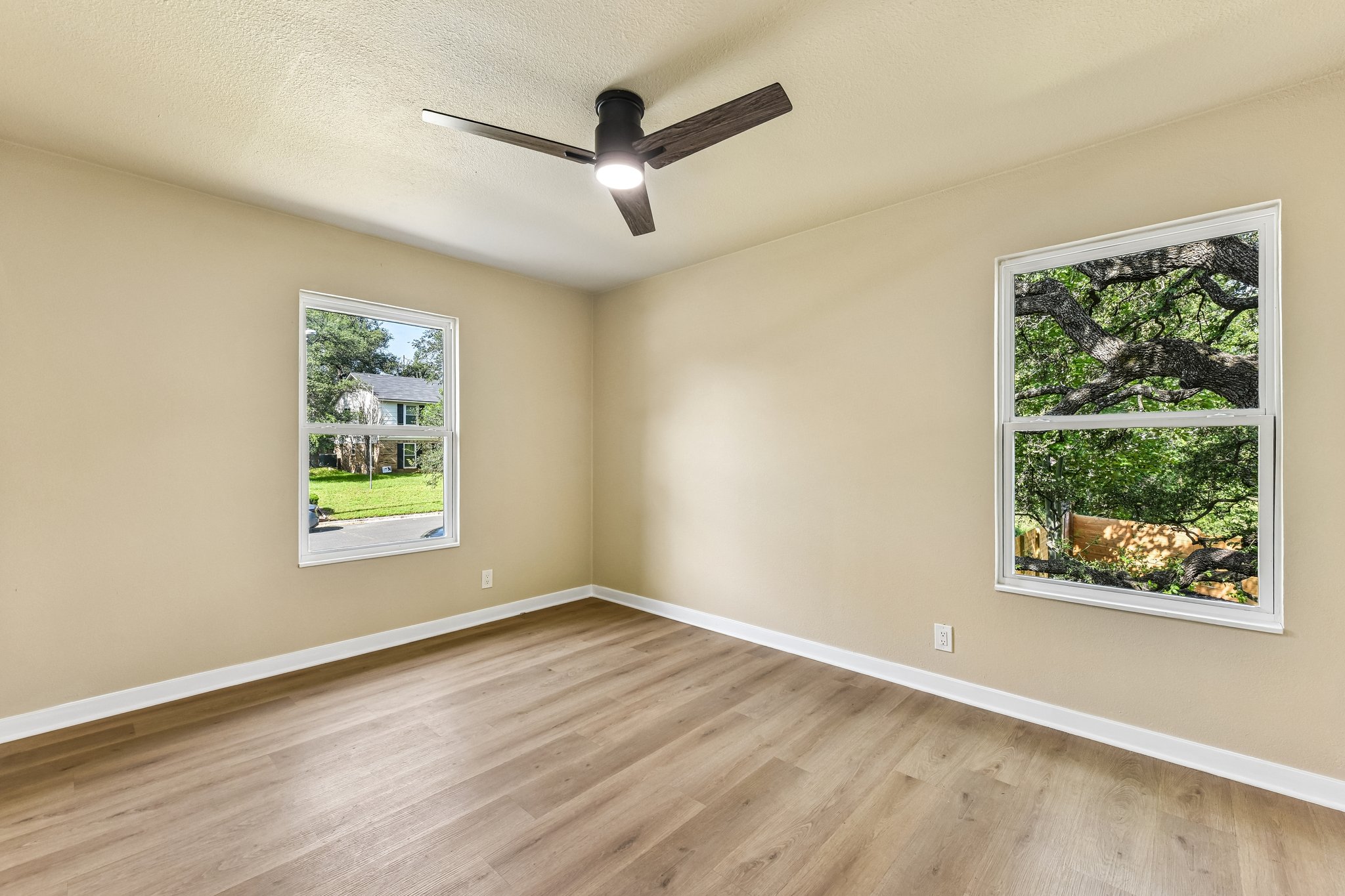 7523 Glenhill Road Austin, TX 78752 - Photo 29 of 38 An airy bedroom with resilient wood flooring and a modern ceiling fan, offering tranquil outdoor views.