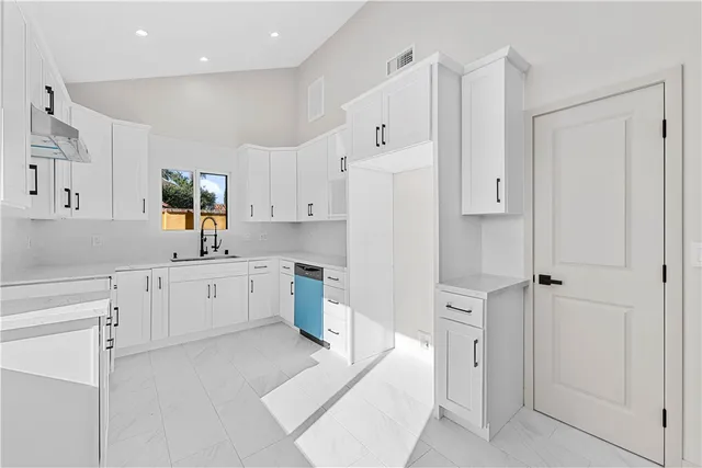 a kitchen with white cabinets and window