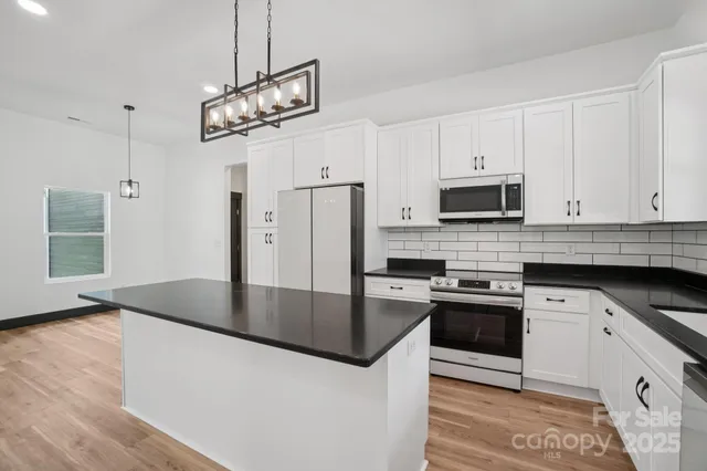 a kitchen with stainless steel appliances granite countertop a sink a stove and a refrigerator