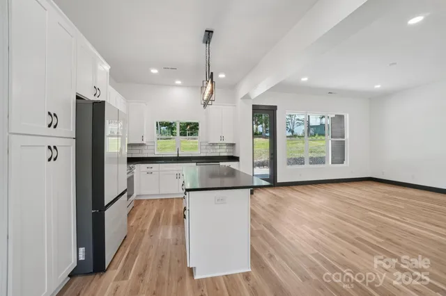 a kitchen with stainless steel appliances granite countertop a refrigerator a oven a sink dishwasher and a stove with wooden floor