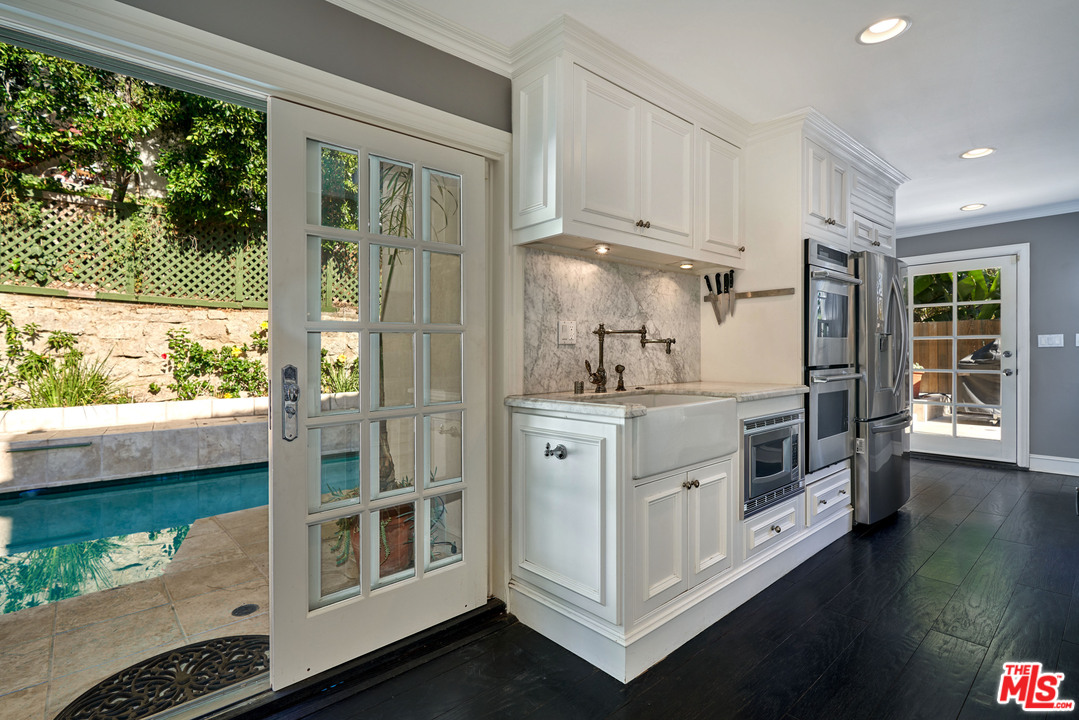 1488 North Kings Road Los Angeles, CA 90069 - Photo 17 of 53 a kitchen with stainless steel appliances white cabinets and wooden floor