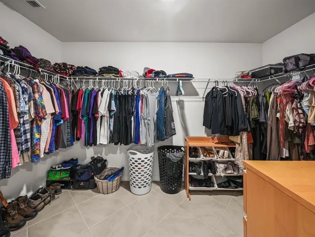a view of walk in closet with clothes and shoes