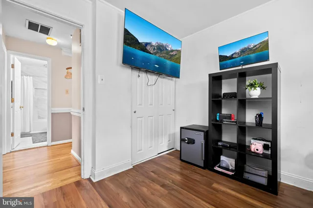 a view of an empty room with wooden floor and closet