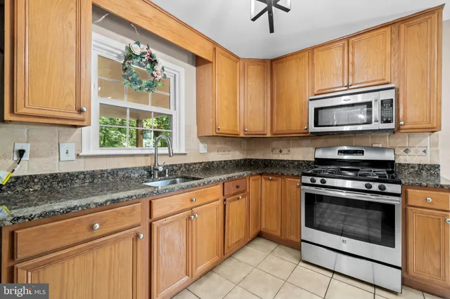 a kitchen with granite countertop cabinets stainless steel appliances a sink and a window