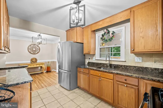 a kitchen with stainless steel appliances granite countertop a refrigerator a sink dishwasher a stove and a dining table with wooden floor