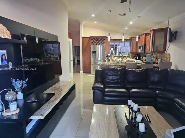 a living room with stainless steel appliances kitchen island granite countertop furniture a rug kitchen view and a chandelier
