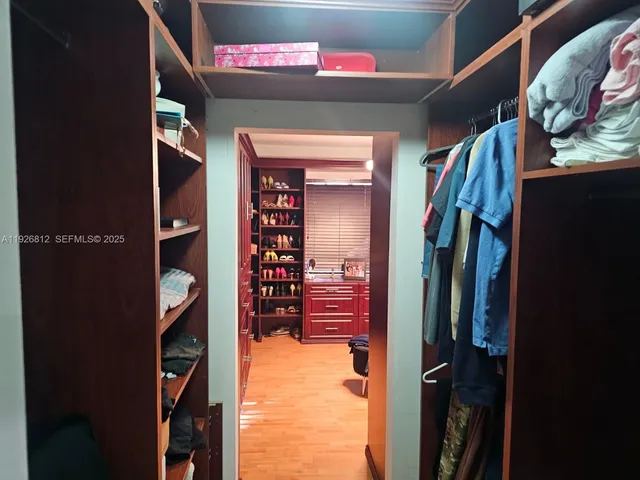 a view of walk in closet with clothes and shoes