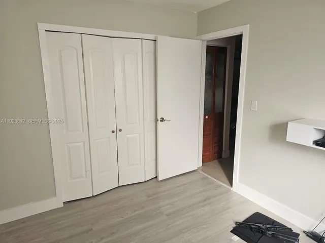 a bedroom with a bed a couch and a flat tv screen on the dresser