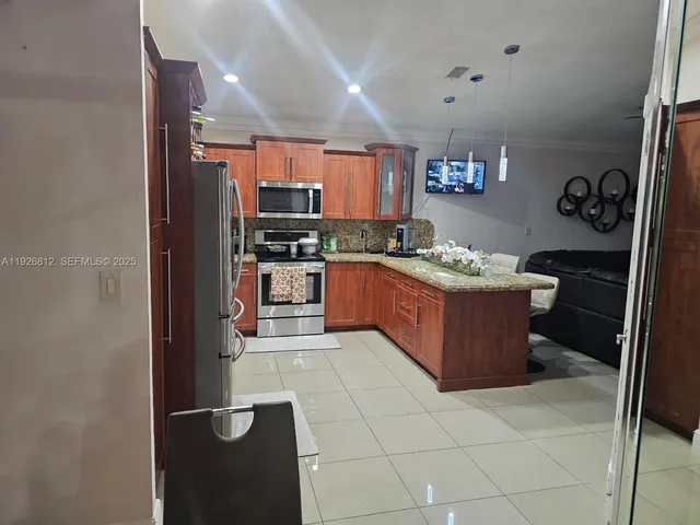 a kitchen with stainless steel appliances granite countertop a stove top oven a sink a counter space and cabinets