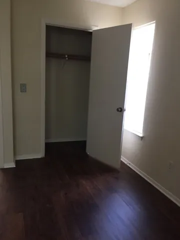 an empty room with wooden floor and closet