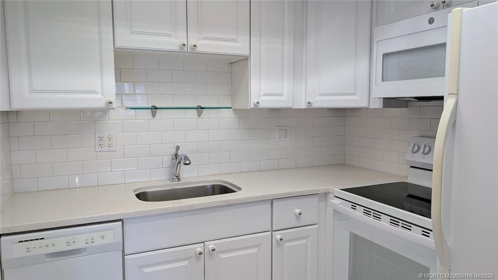 Undisclosed Address Stuart, FL 34996 - Photo 6 of 28 a kitchen with white cabinets and white appliances